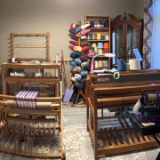 Two looms and shelves of yarn in a room